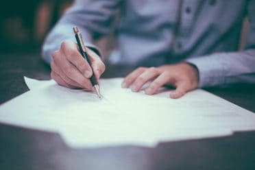 a person holding a pen, signing a document or making a contract